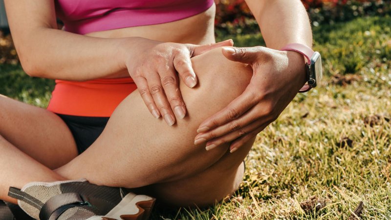 woman with knee pain sitting on grass