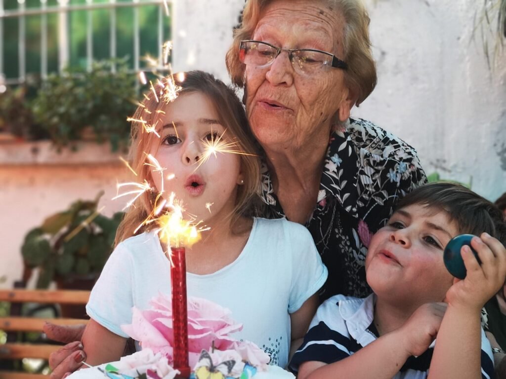 Grandmother with two young children blowing out birthday candle